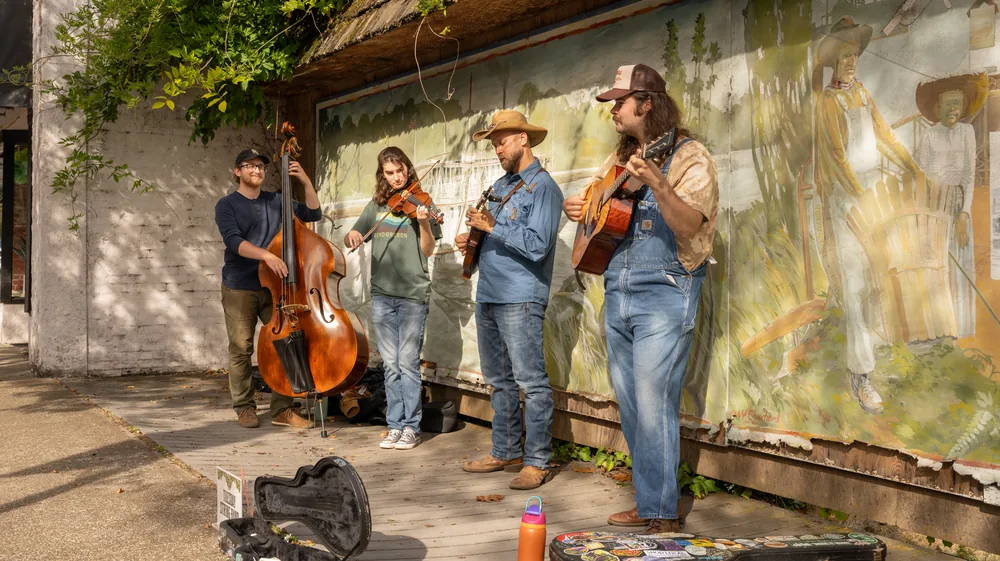 A string band busking in front of a painted mural in downtown Independence