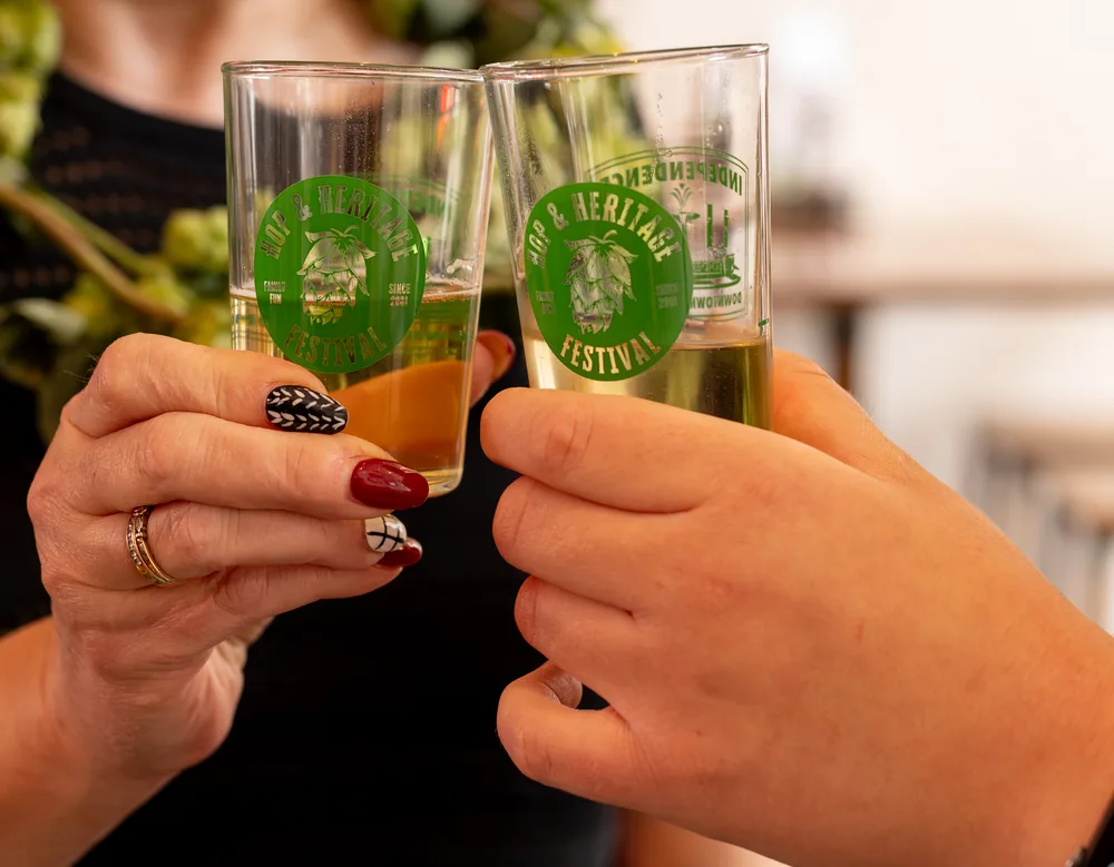 Two festival tasting glasses raised in a toast at the Hop and Heritage Festival