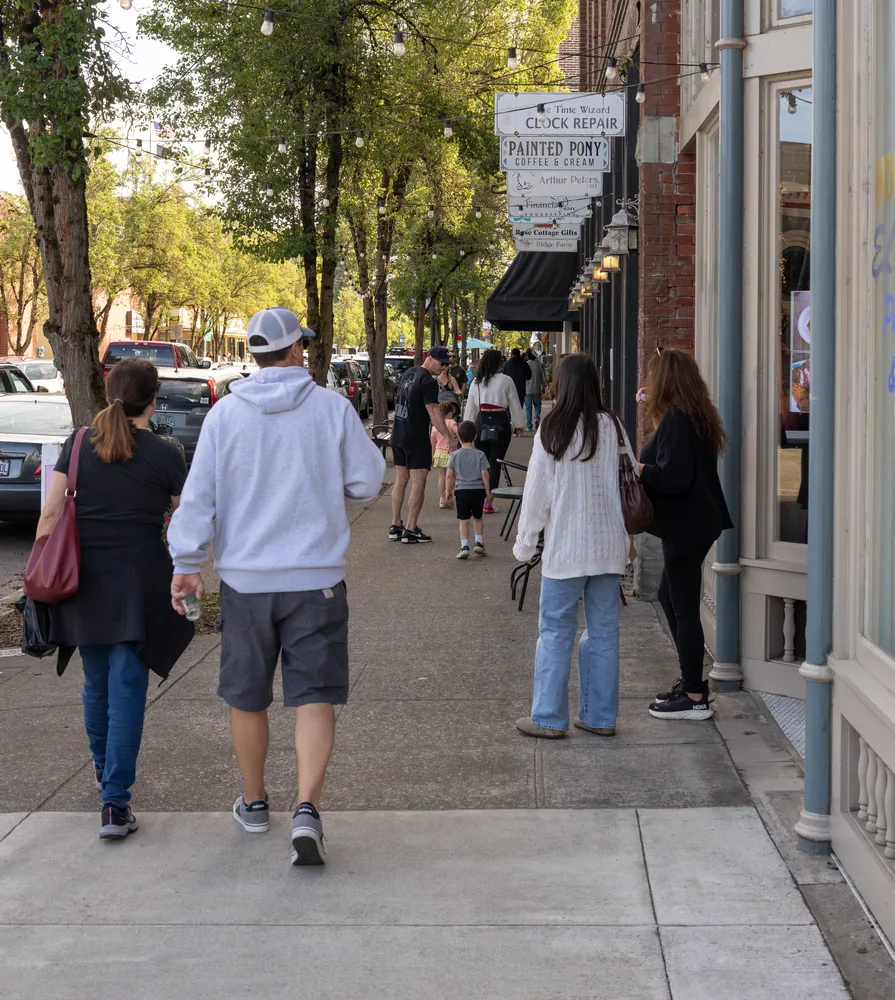 Festival guests walking a tree-lined sidewalk in downtown Independence, Oregon